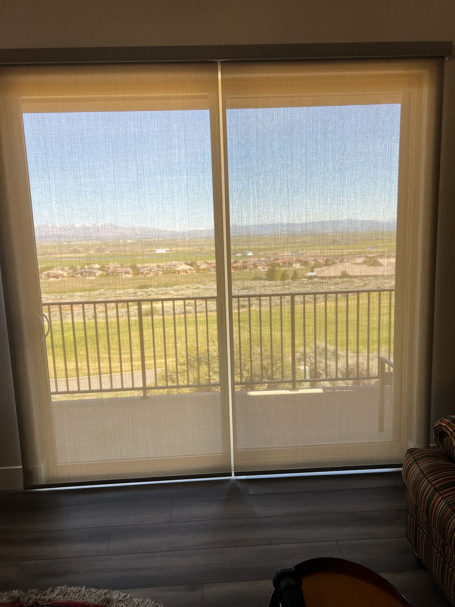 Living room sliding glass doors with sheer curtains, overlooking a bright balcony and distant landscape