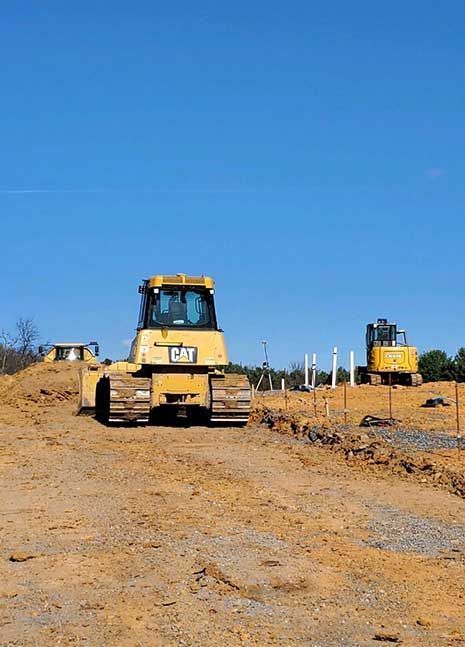 A bulldozer is driving down a dirt road on a construction site.