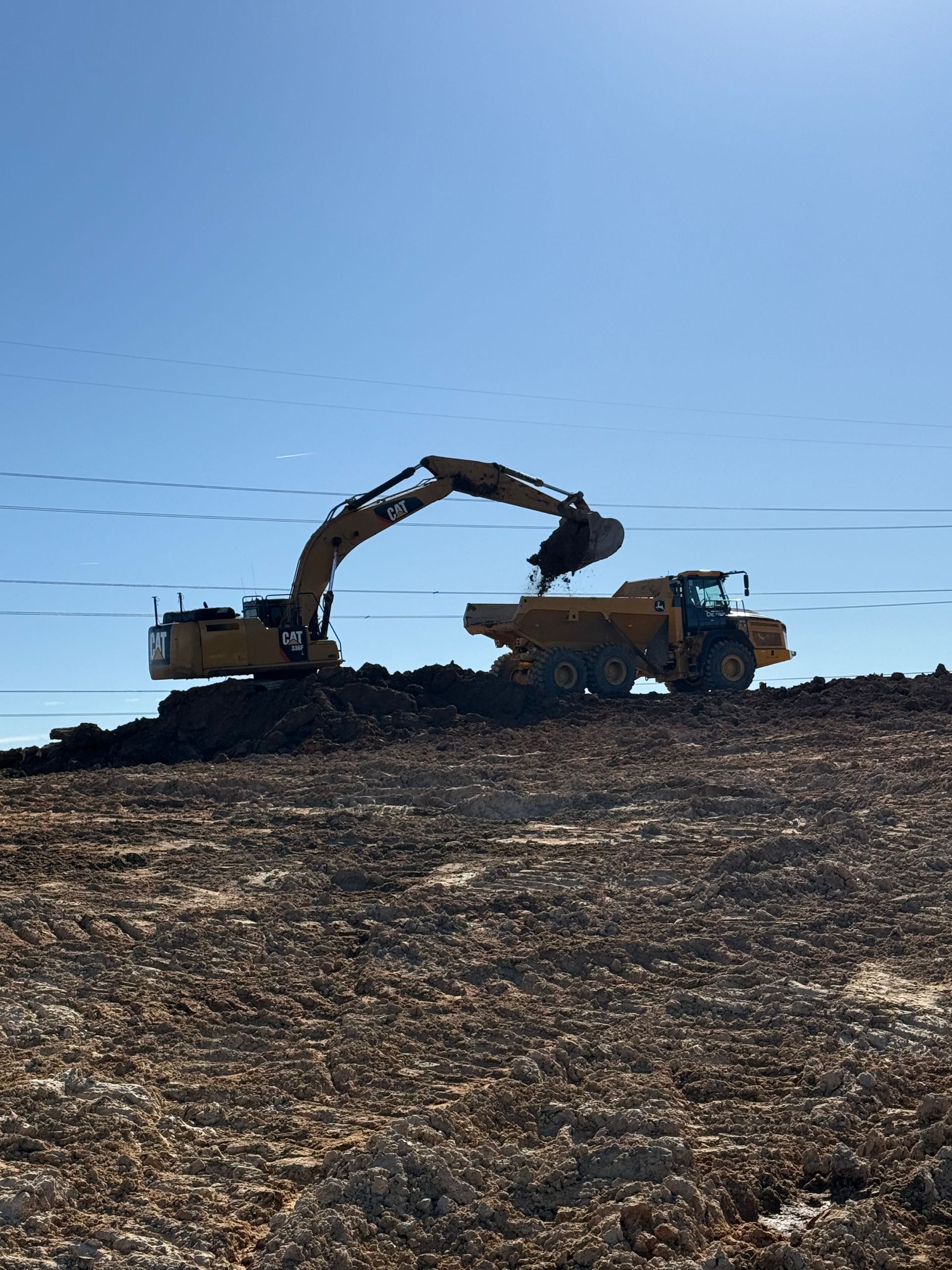 A bulldozer is scooping dirt and branches from the ground.