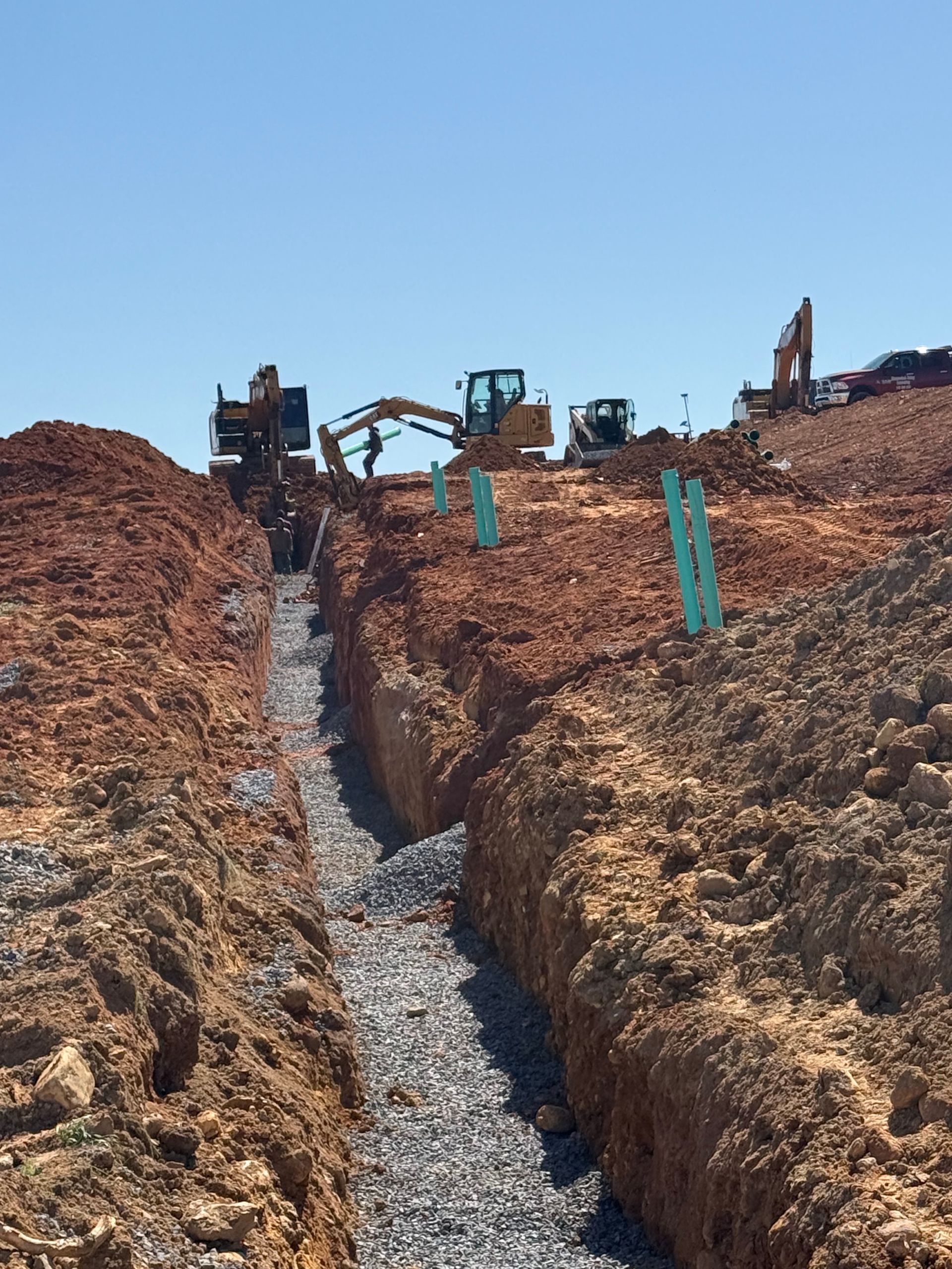 A group of construction workers are working on a pipe in a trench.