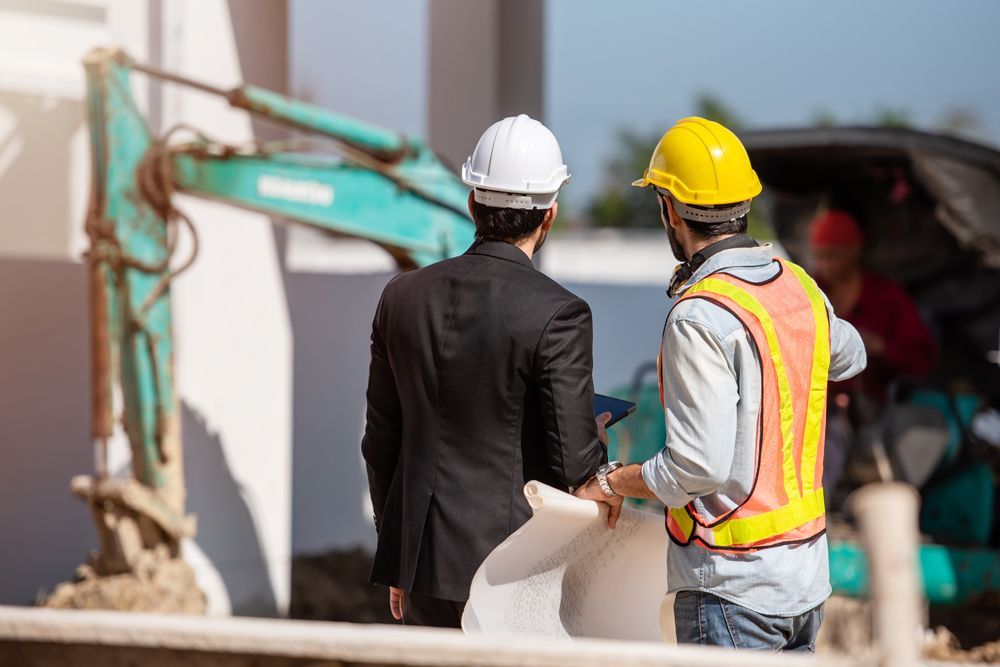 Two construction workers are standing next to each other at a construction site.