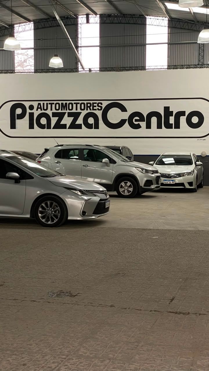 Coches aparcados dentro de una sala de exposición de Automotores Piazza Centro con un gran cartel en la pared.