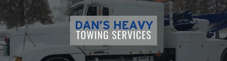 White tow truck in snowy conditions with logo reading 