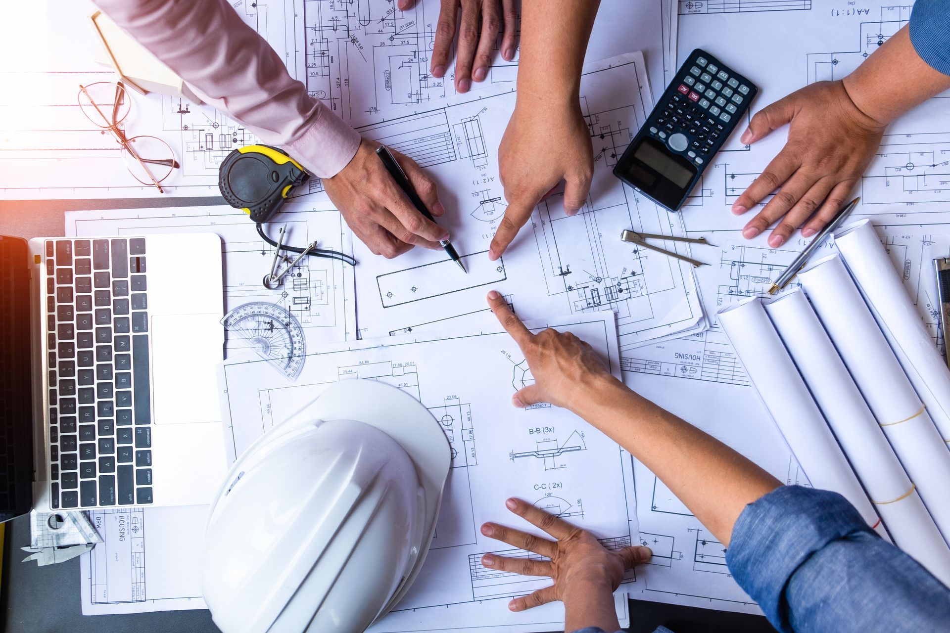 Team of architects examining blueprints on a table, pointing and discussing a construction plan.