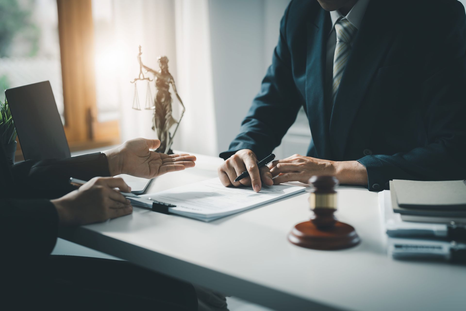 Business meeting at a desk with documents, a gavel, and two people reviewing papers.