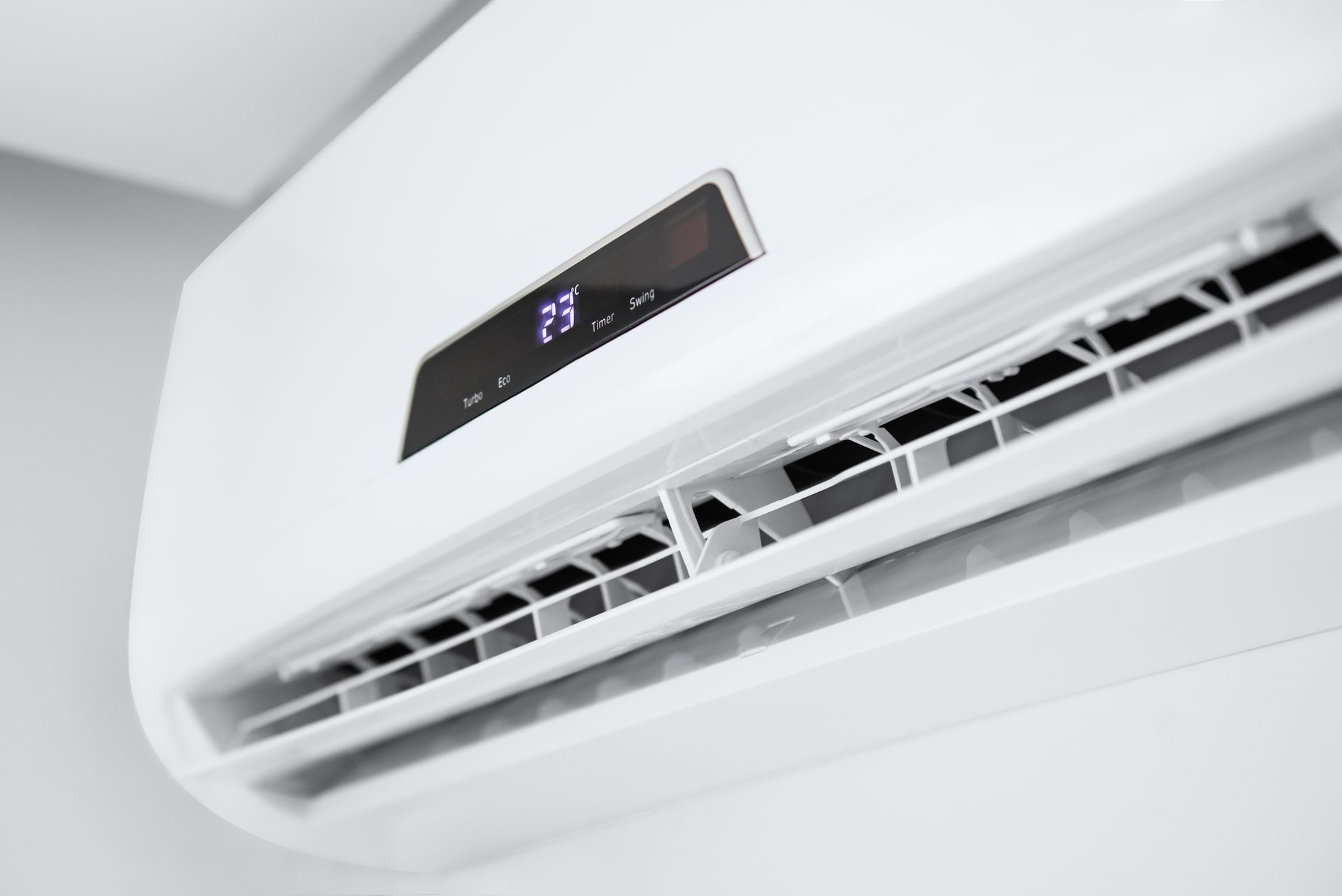 White air conditioner mounted on a wall with temperature display.