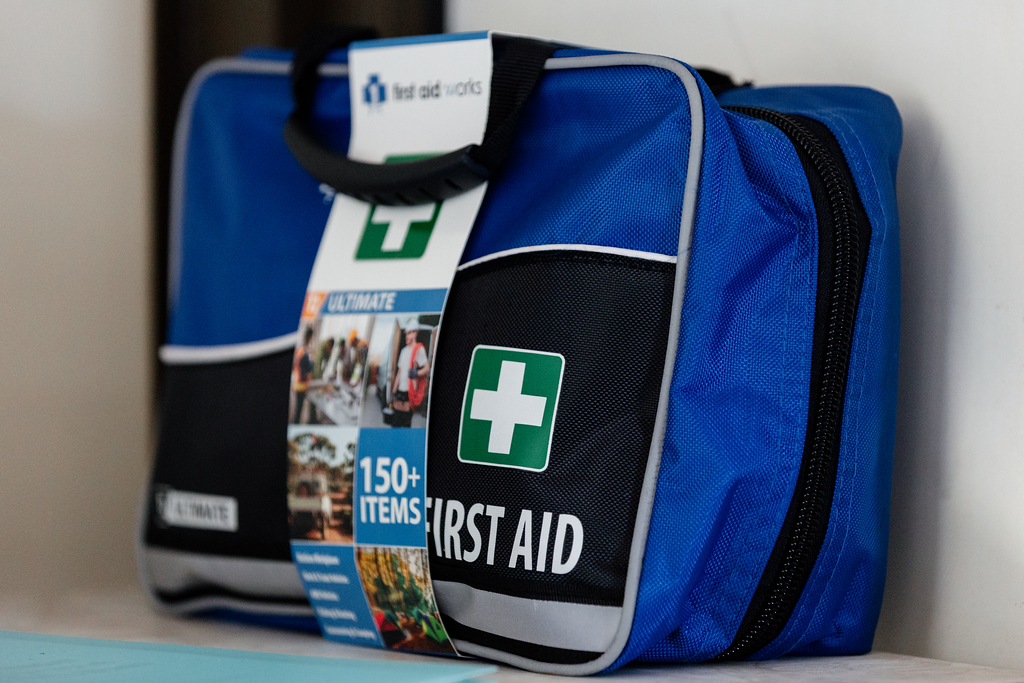 Blue first aid kit with a white and green cross, containing over 150 items.