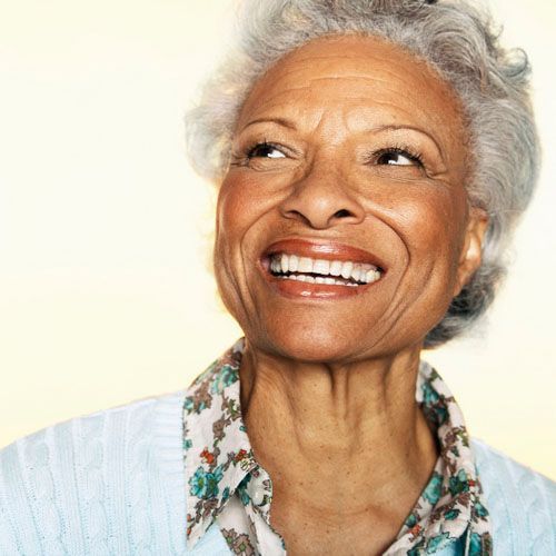 Smiling woman with short gray hair looking upward against a light background