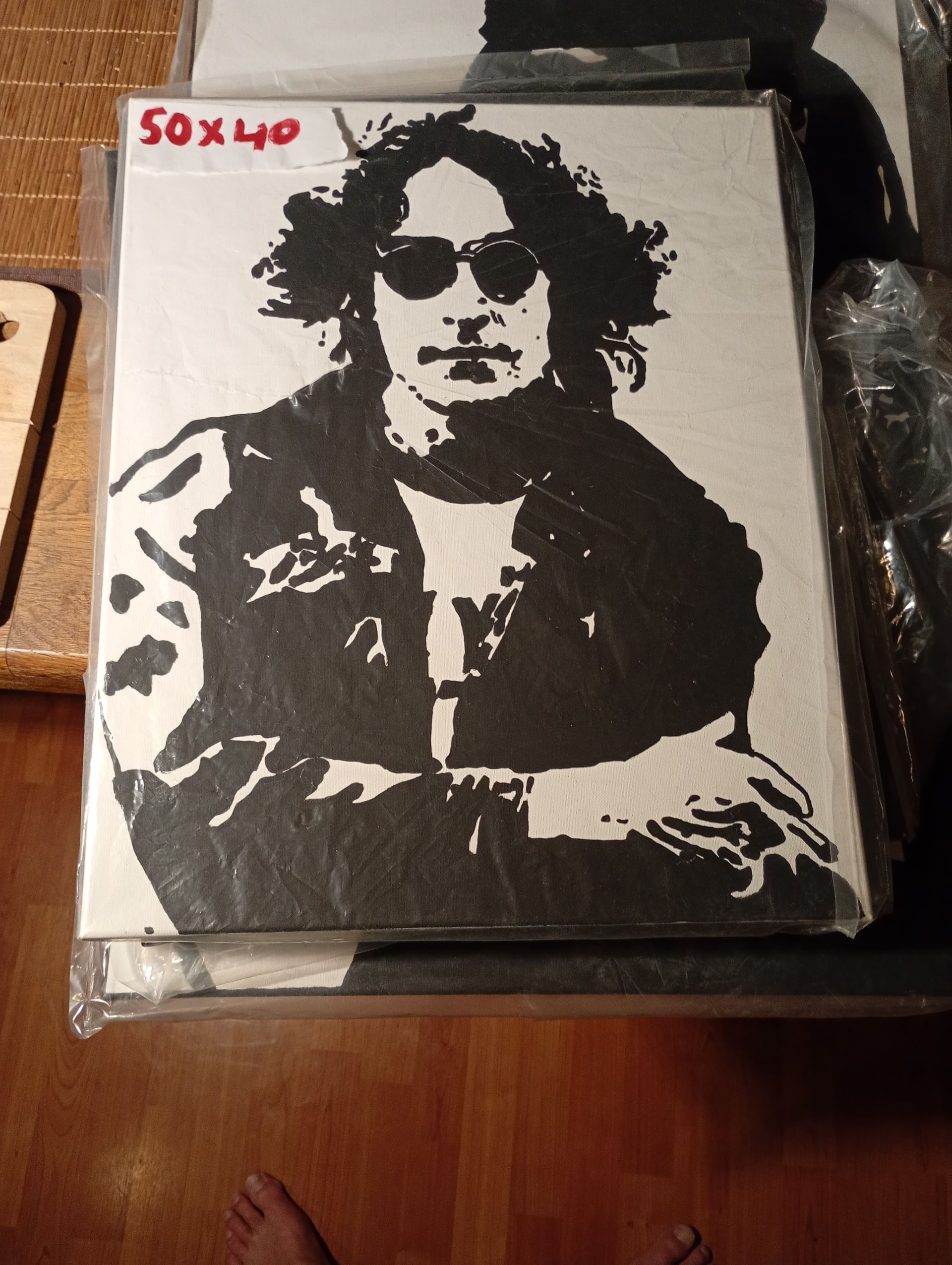 Zwart-wit stencilkunst van John Lennon met een zonnebril, 50x40 cm, in een plastic hoes.