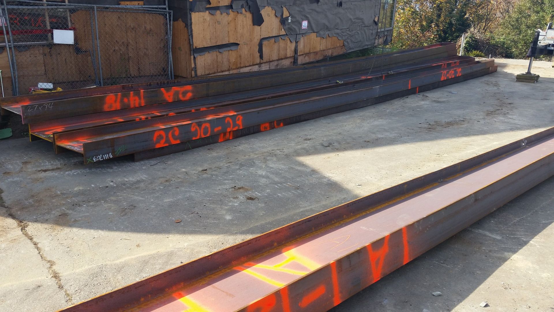 A bunch of metal beams are stacked on top of each other in a parking lot.