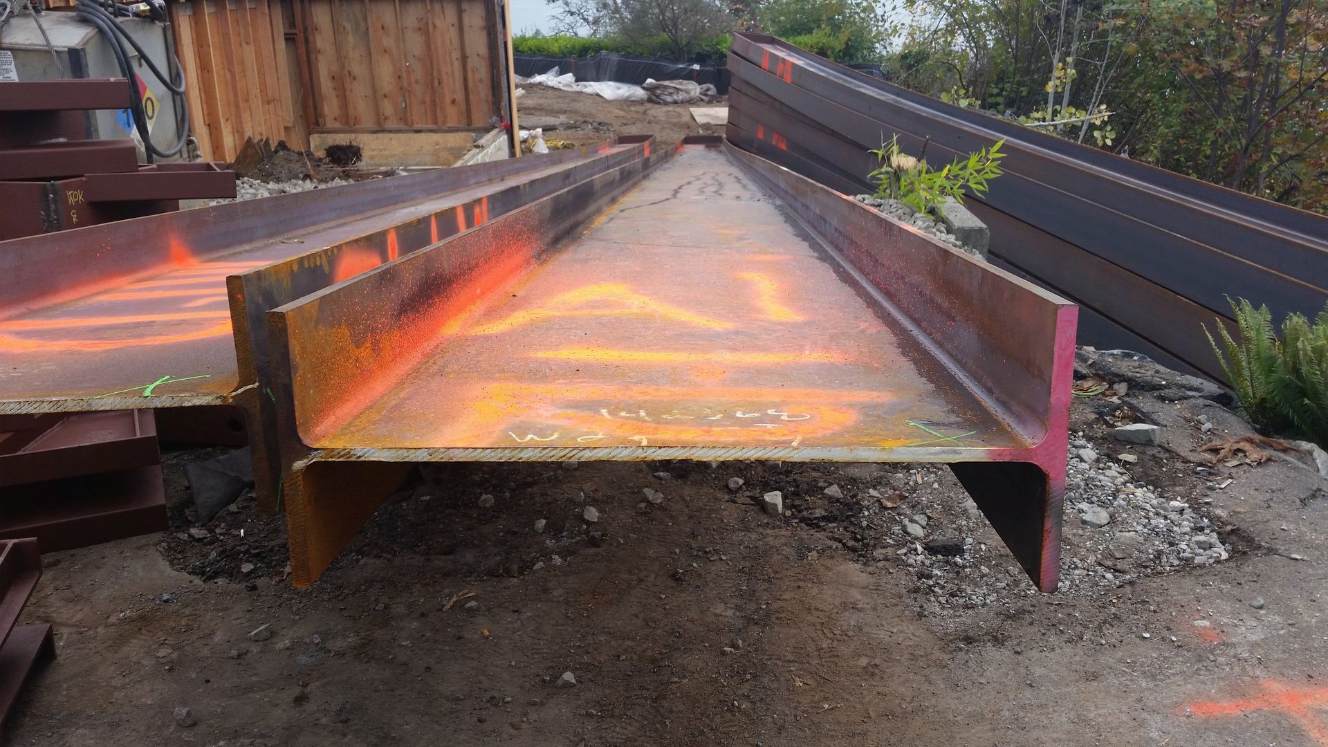 A large metal beam is sitting on top of a dirt field.