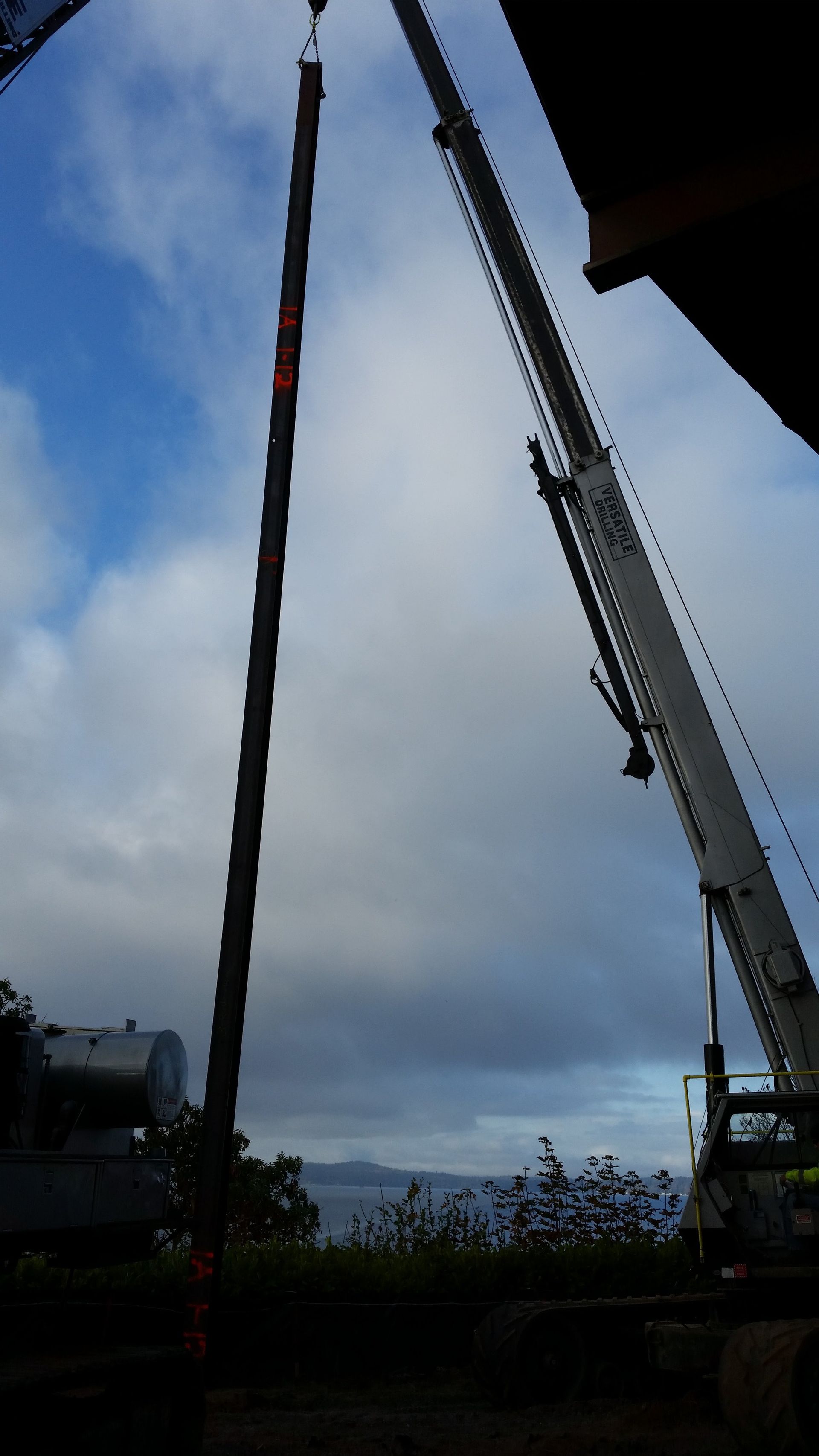 A large white crane is lifting something in the sky