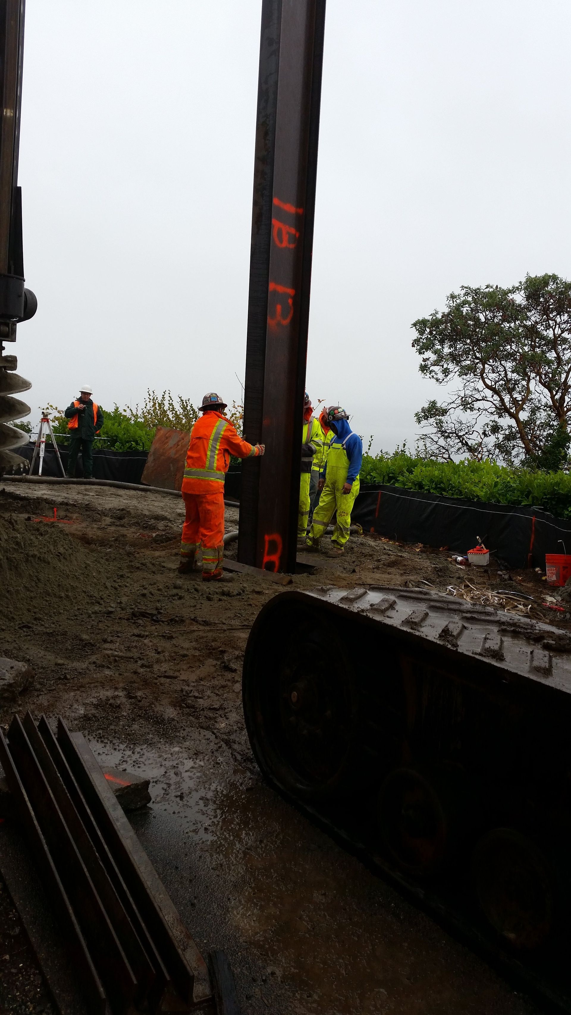 A group of construction workers are standing around a large pole.
