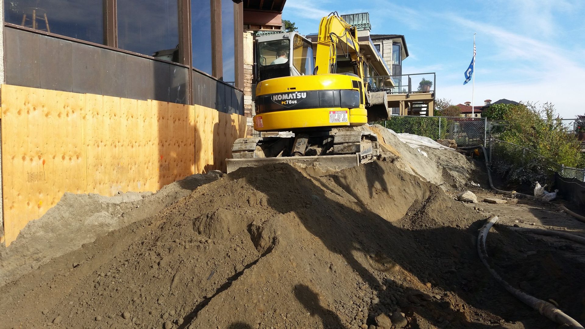 A yellow excavator is working on a pile of dirt