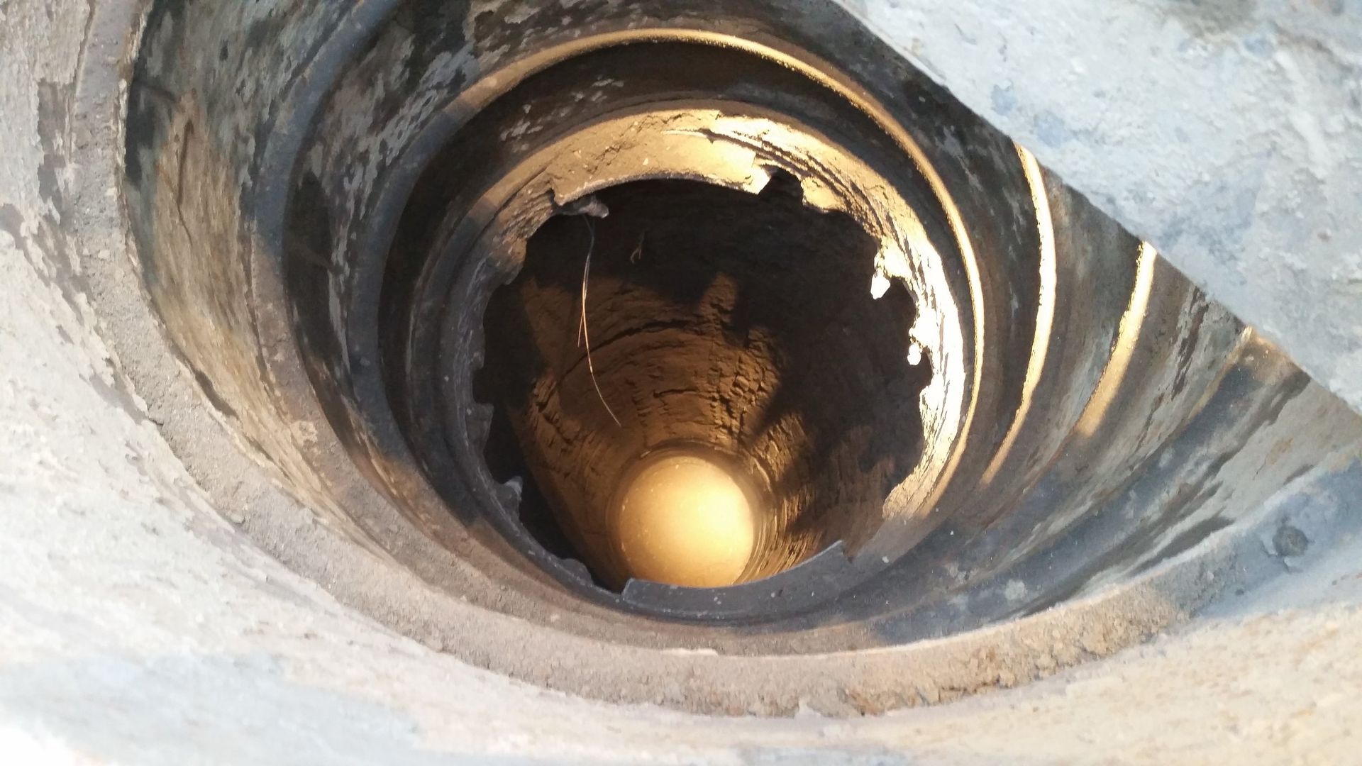 A close up of a hole in the ground with a yellow object in it.