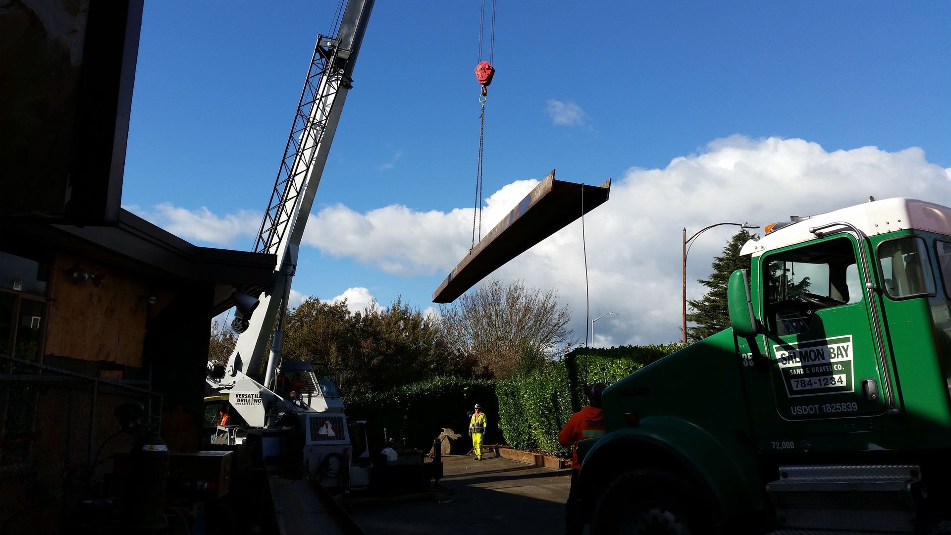 A green truck is being lifted by a crane