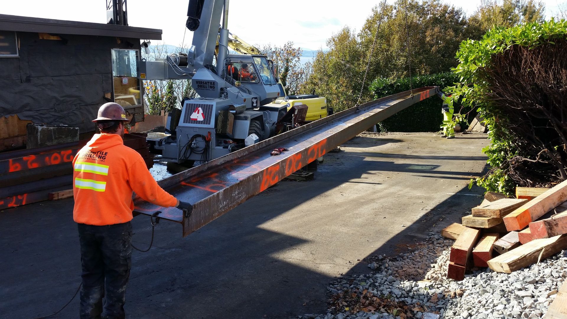 A man in an orange jacket is standing next to a tow truck.