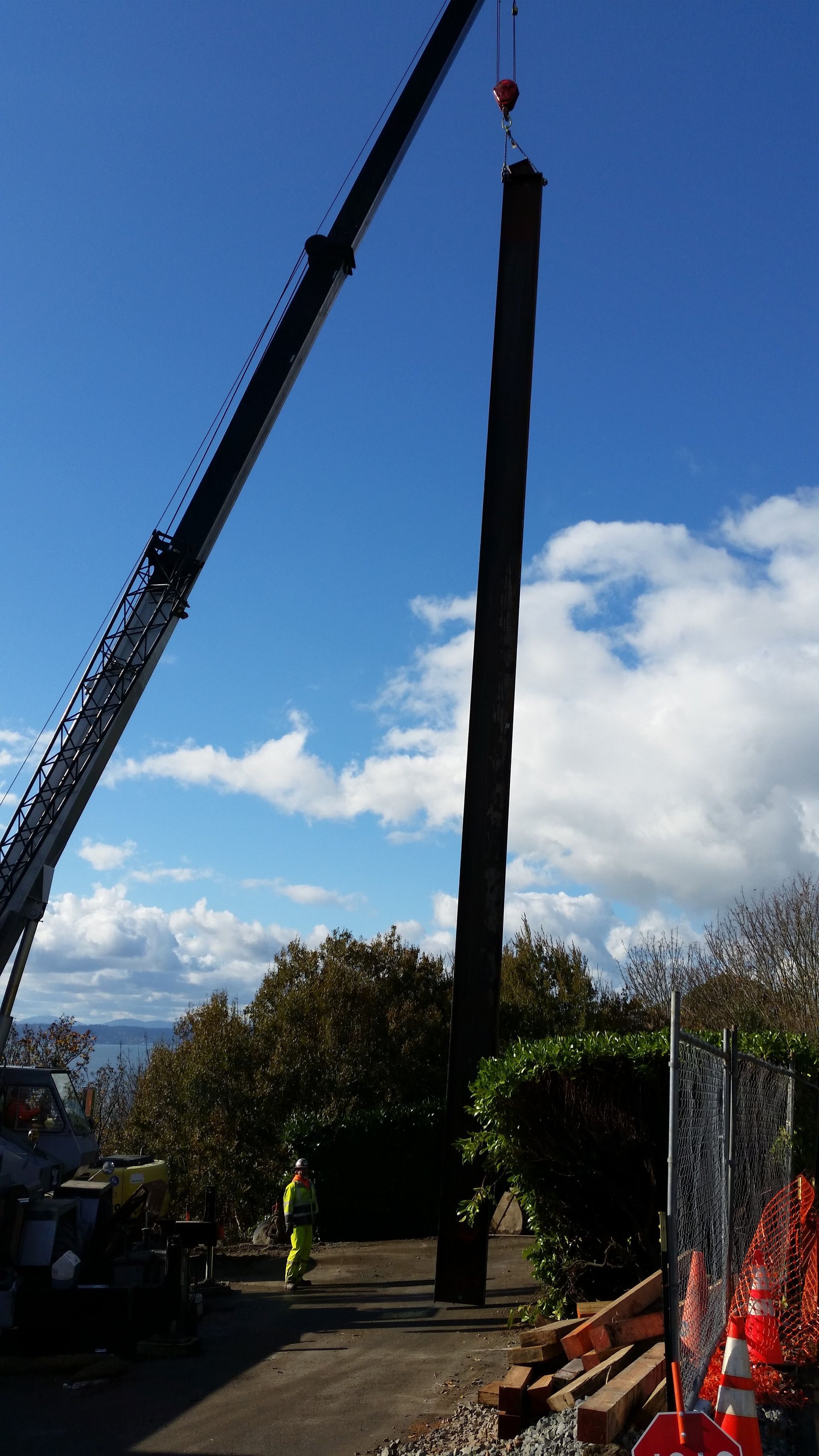 A crane is lifting a large pole in the air.