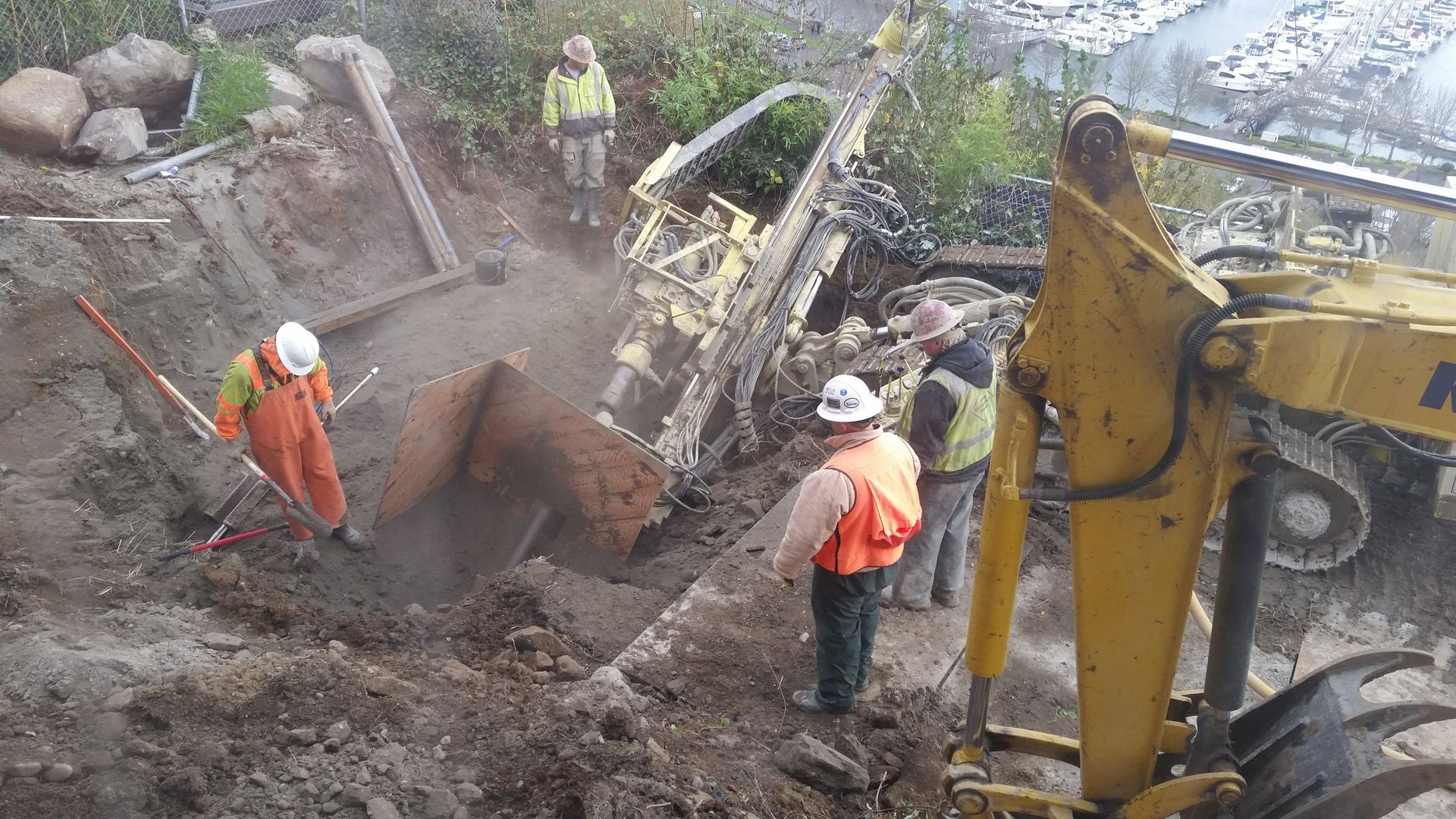 A group of construction workers are digging a hole in the dirt.