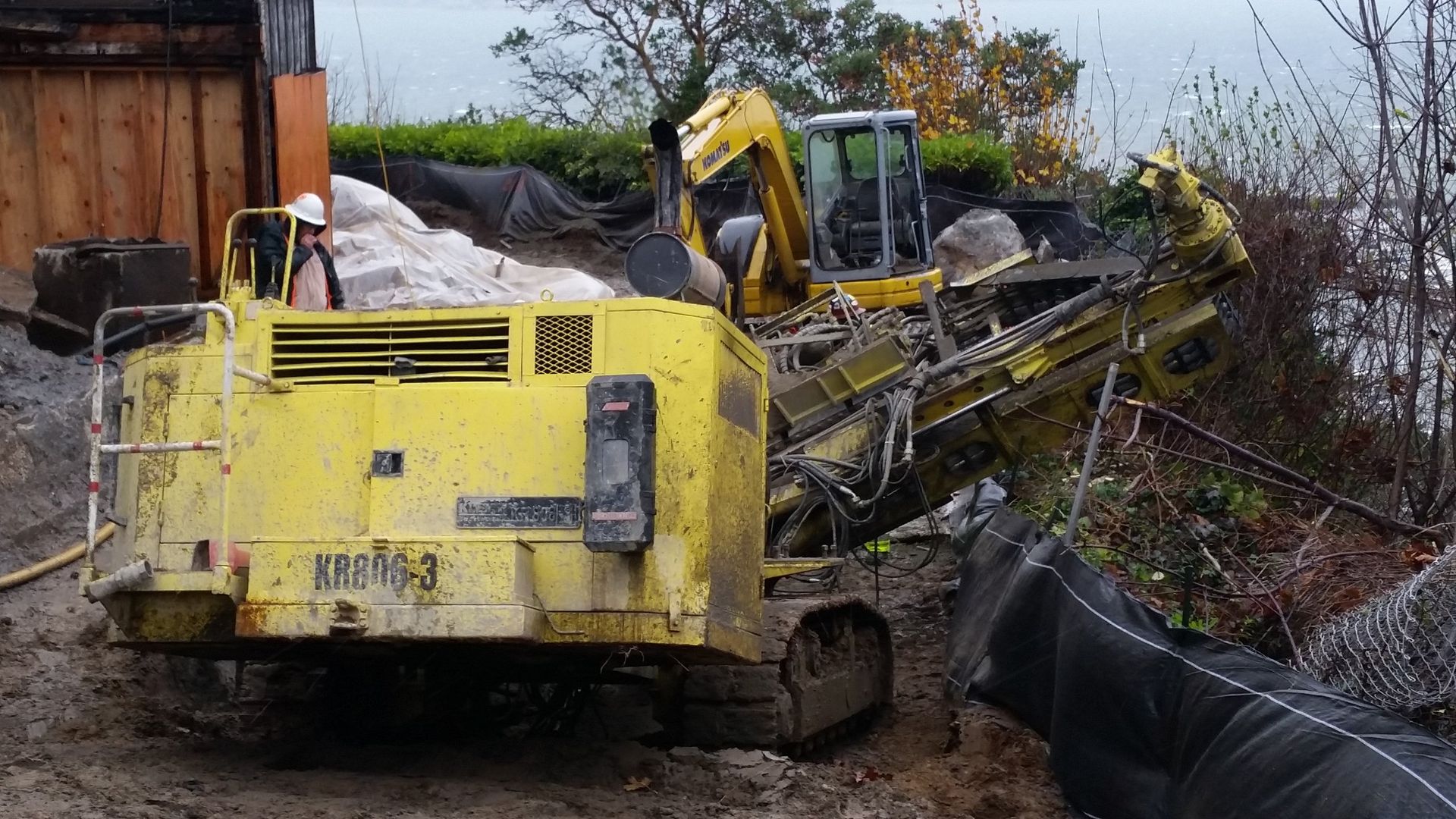 A yellow excavator is parked in the dirt next to a smaller yellow excavator.