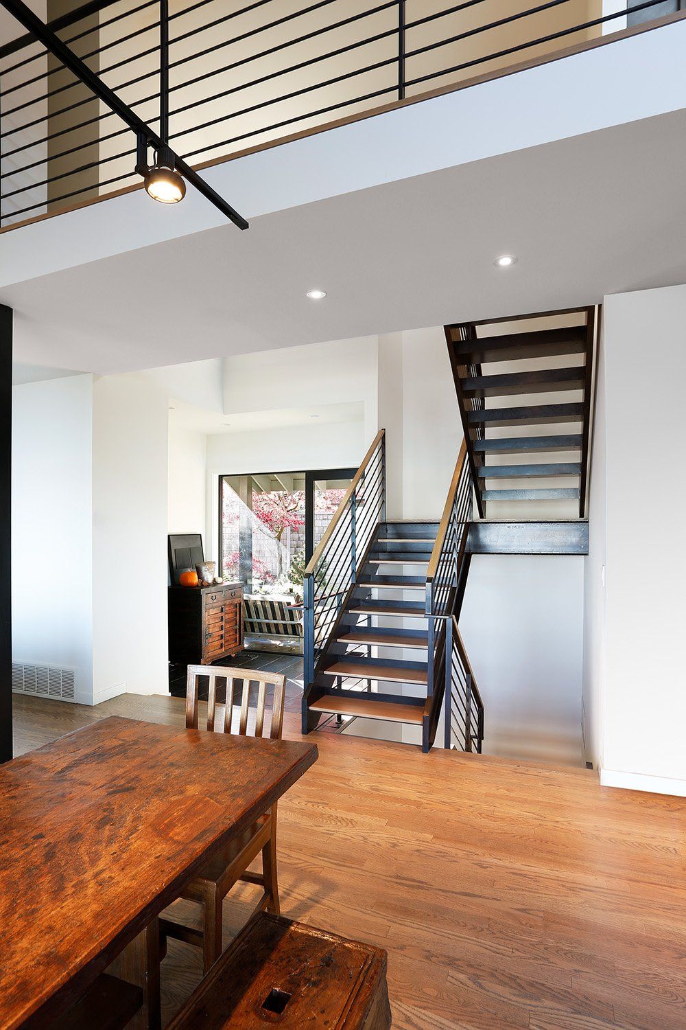 A dining room with a table and chairs and a staircase leading to the second floor.