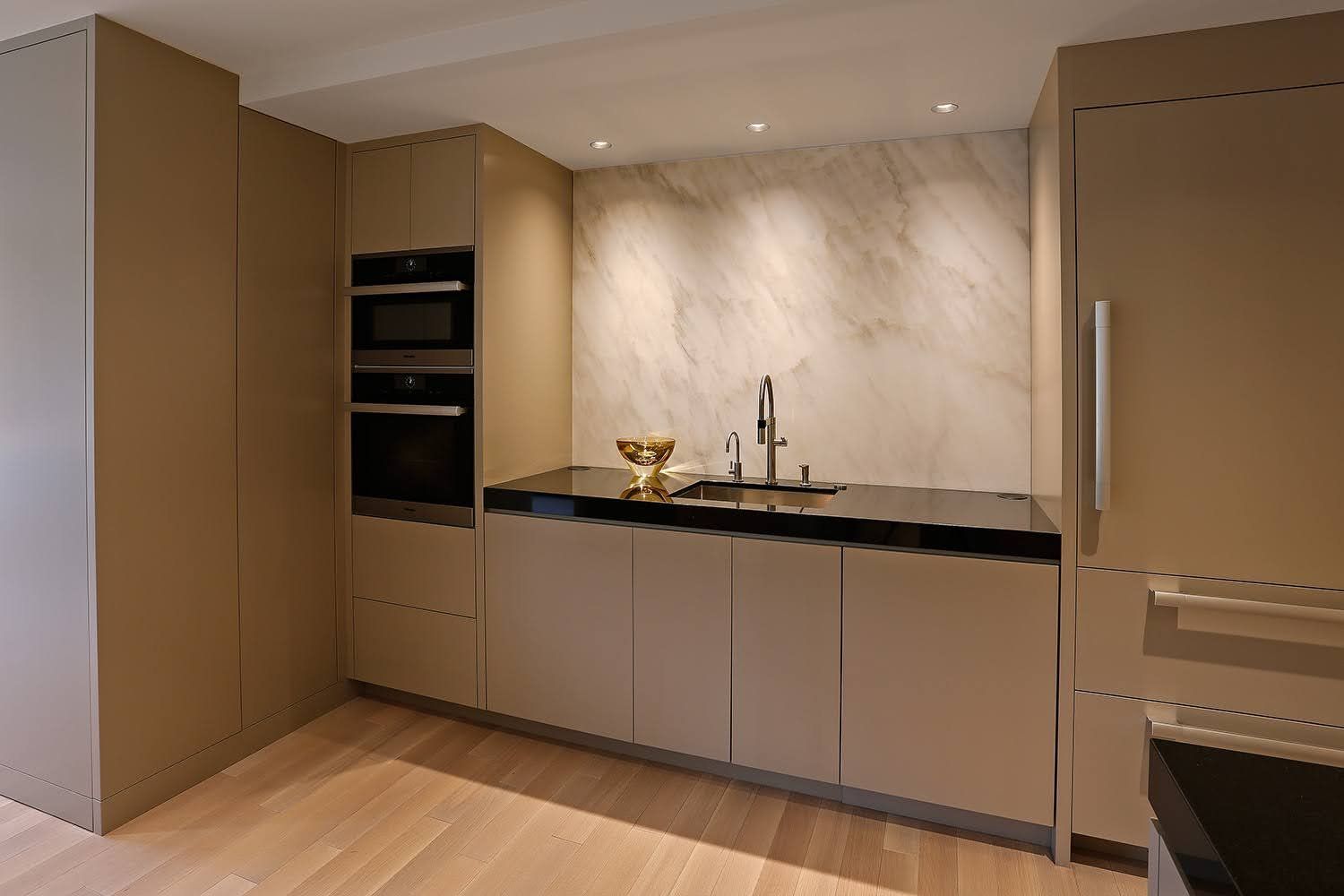 A kitchen with a sink , refrigerator , oven and microwave.