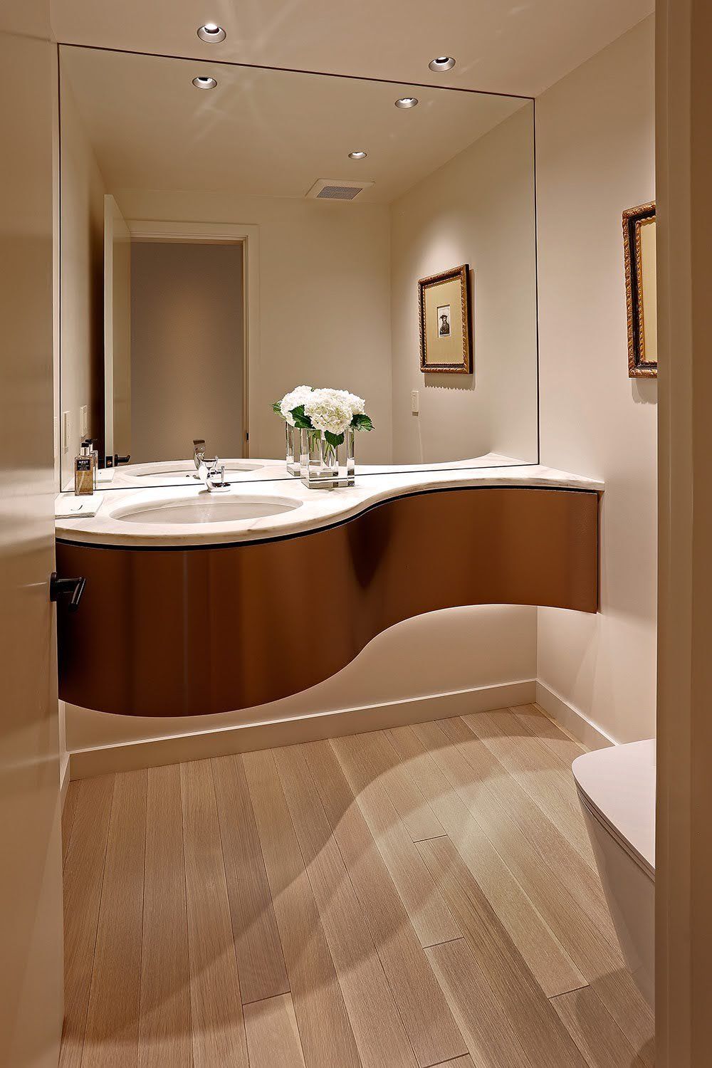A bathroom with a curved sink and a large mirror