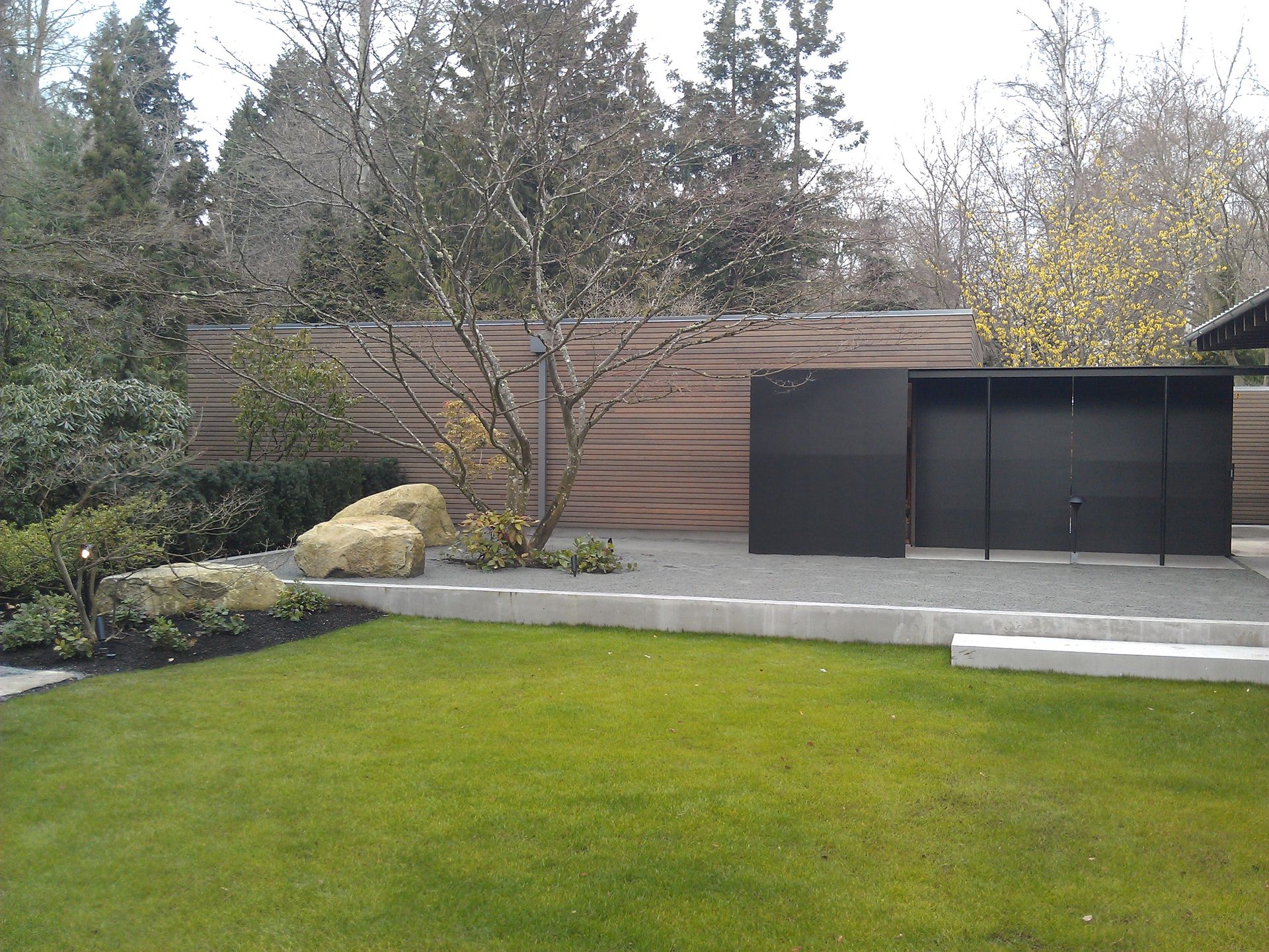 A backyard with a fence and a black garage door