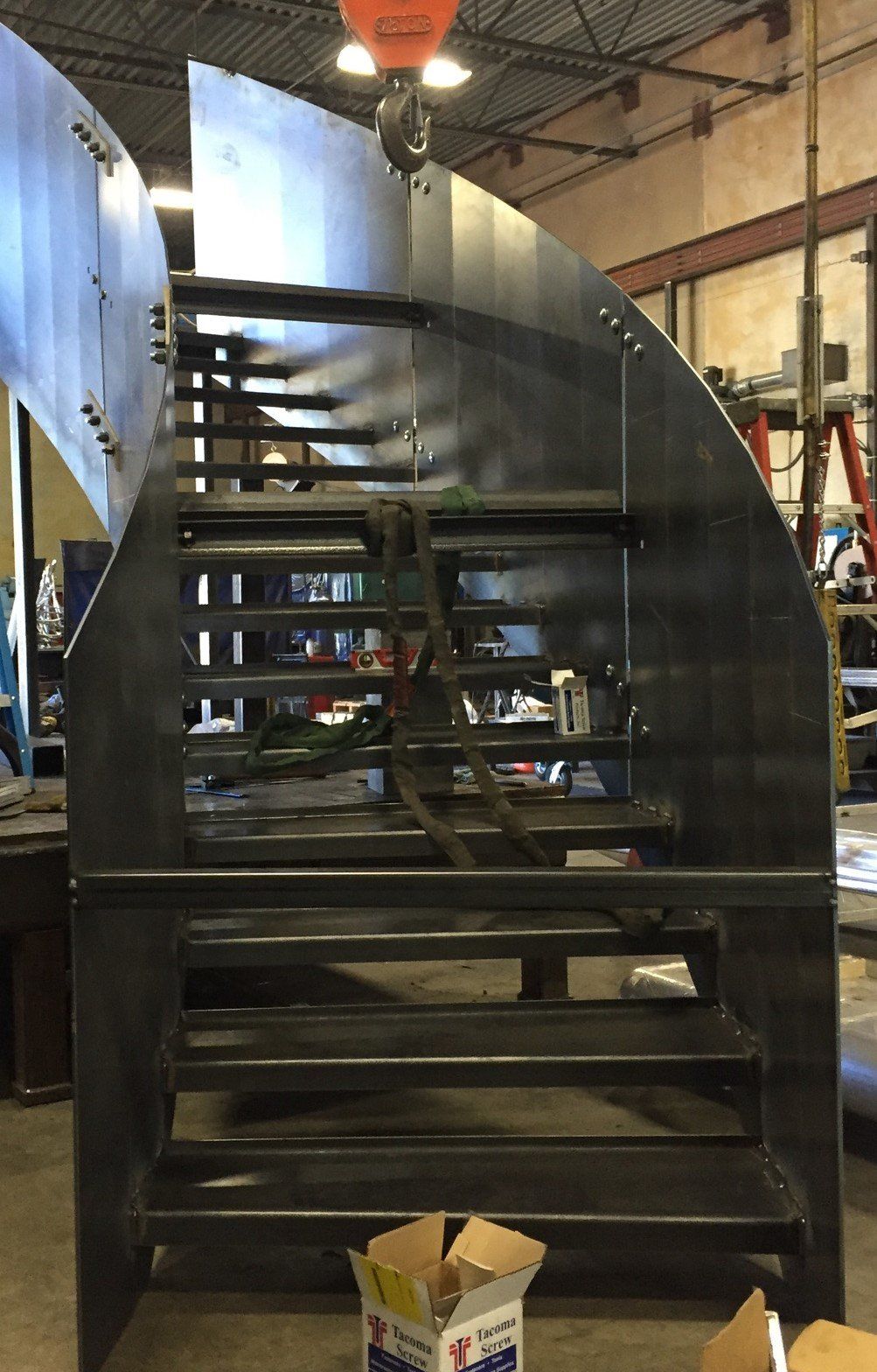 A metal staircase is being built in a factory.