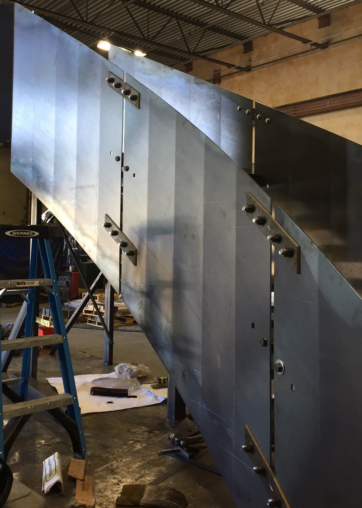 A large metal staircase is being built in a factory.