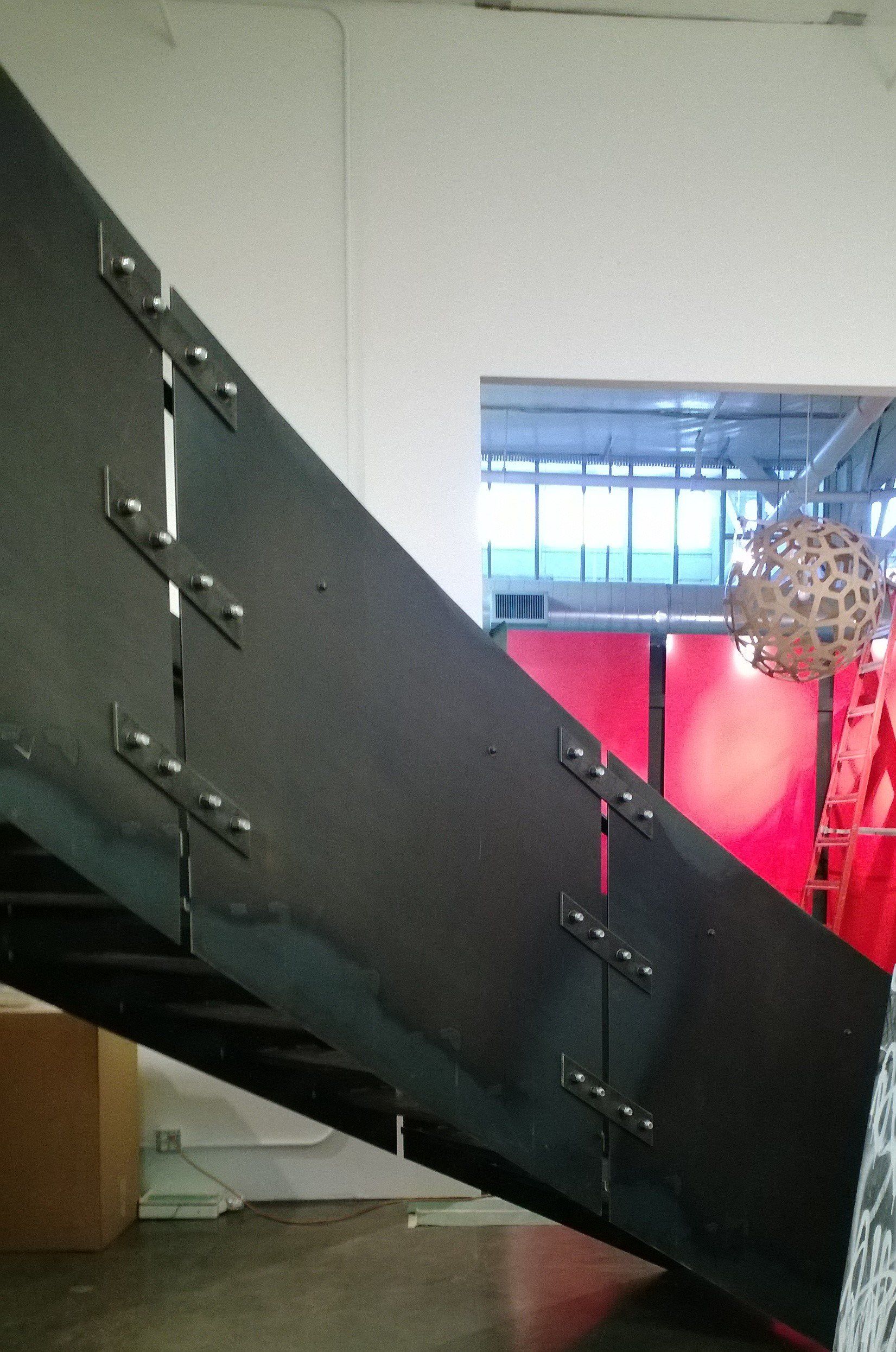 A black staircase with a red wall in the background