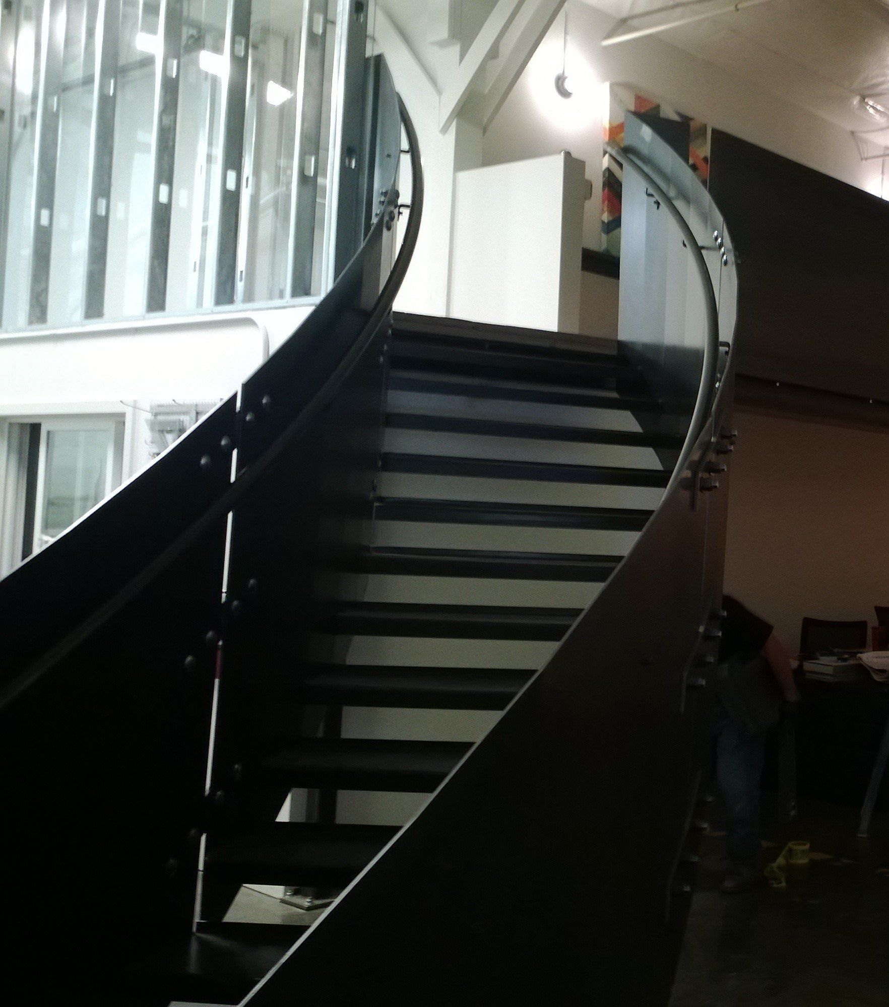 A spiral staircase with a glass railing in a dark room