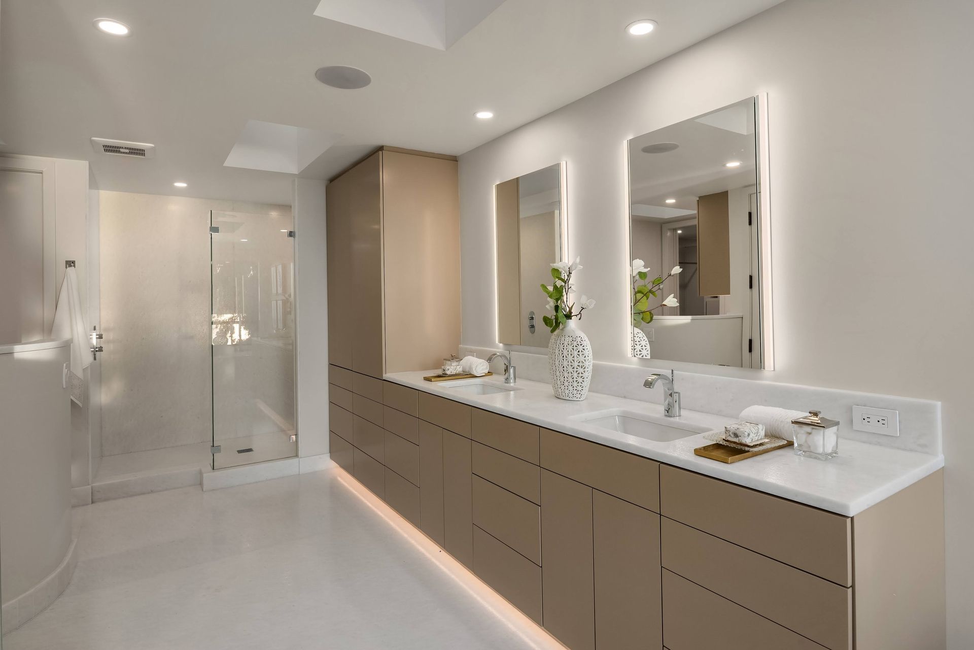 A bathroom with two sinks , two mirrors and a walk in shower.