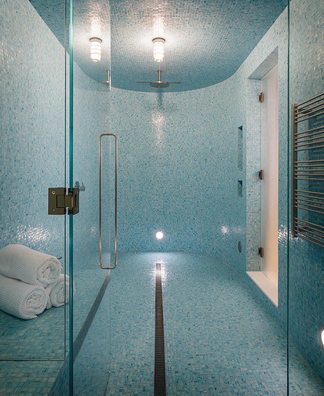 A bathroom with blue tiles and a walk in shower