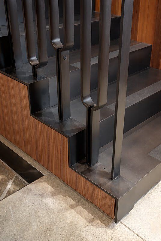A close up of a staircase with a metal railing and wooden steps.