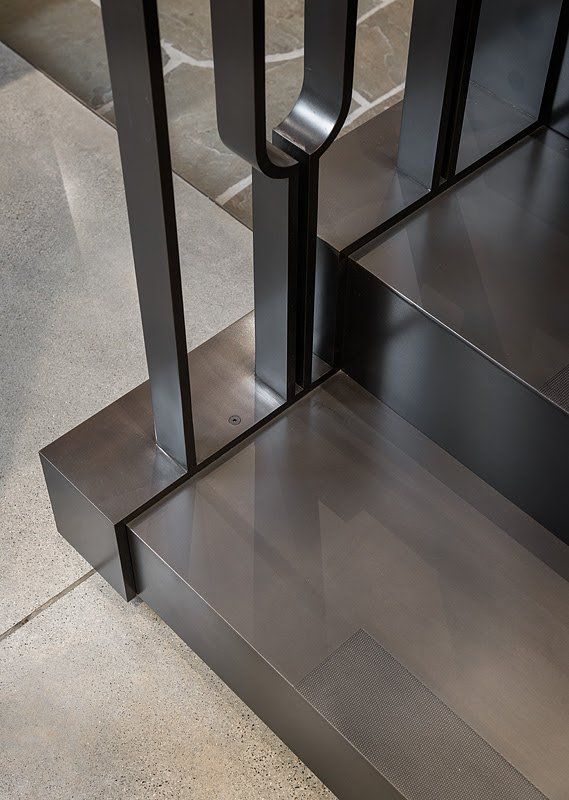 A close up of a stainless steel staircase with a black railing.