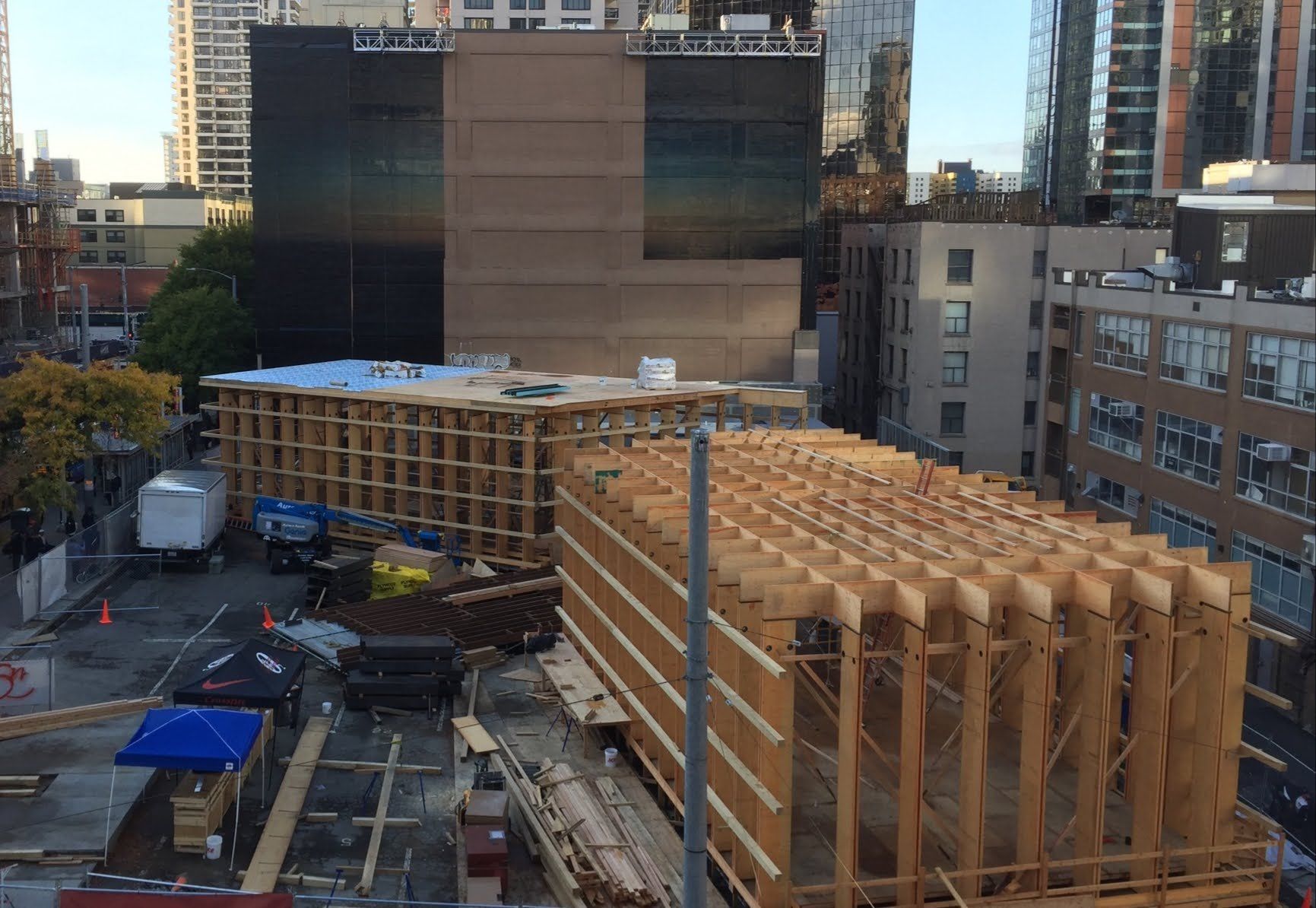 A large wooden structure is being built in the middle of a city.