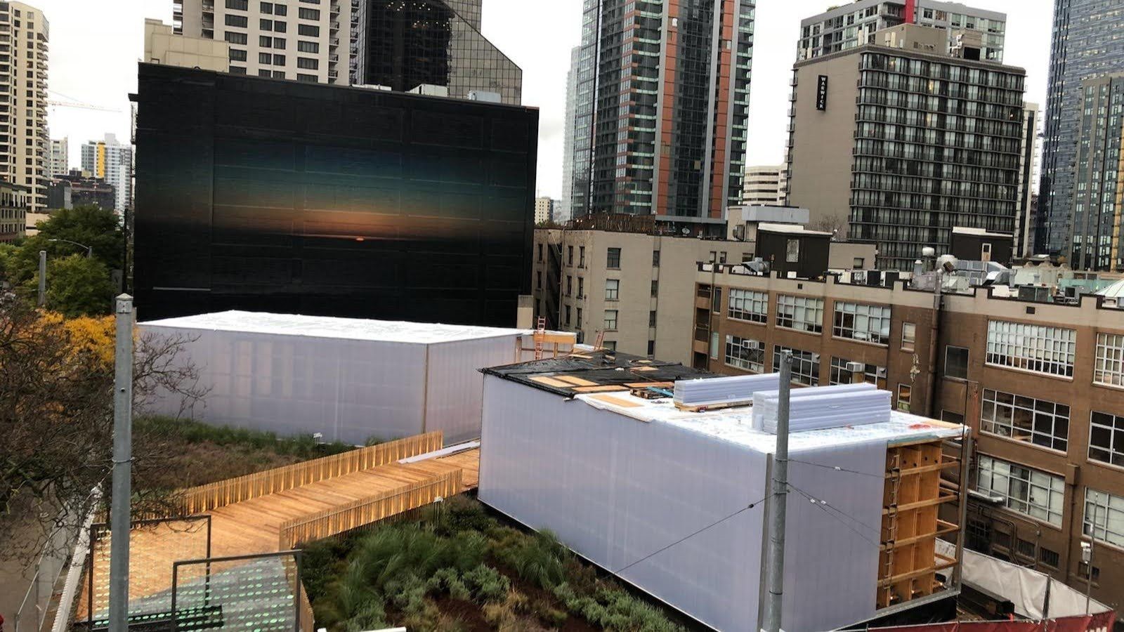 A large billboard is sitting on top of a building in a city.