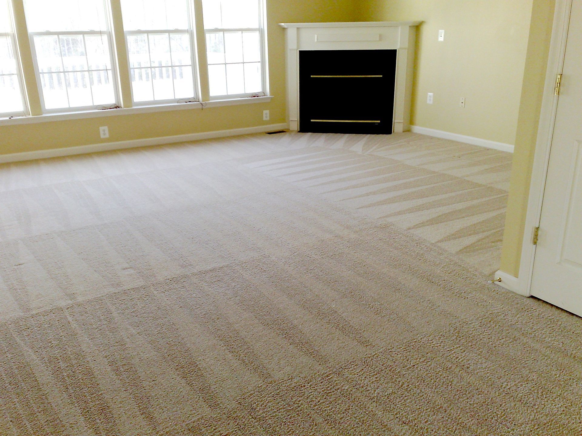 An empty living room with a fireplace in the corner