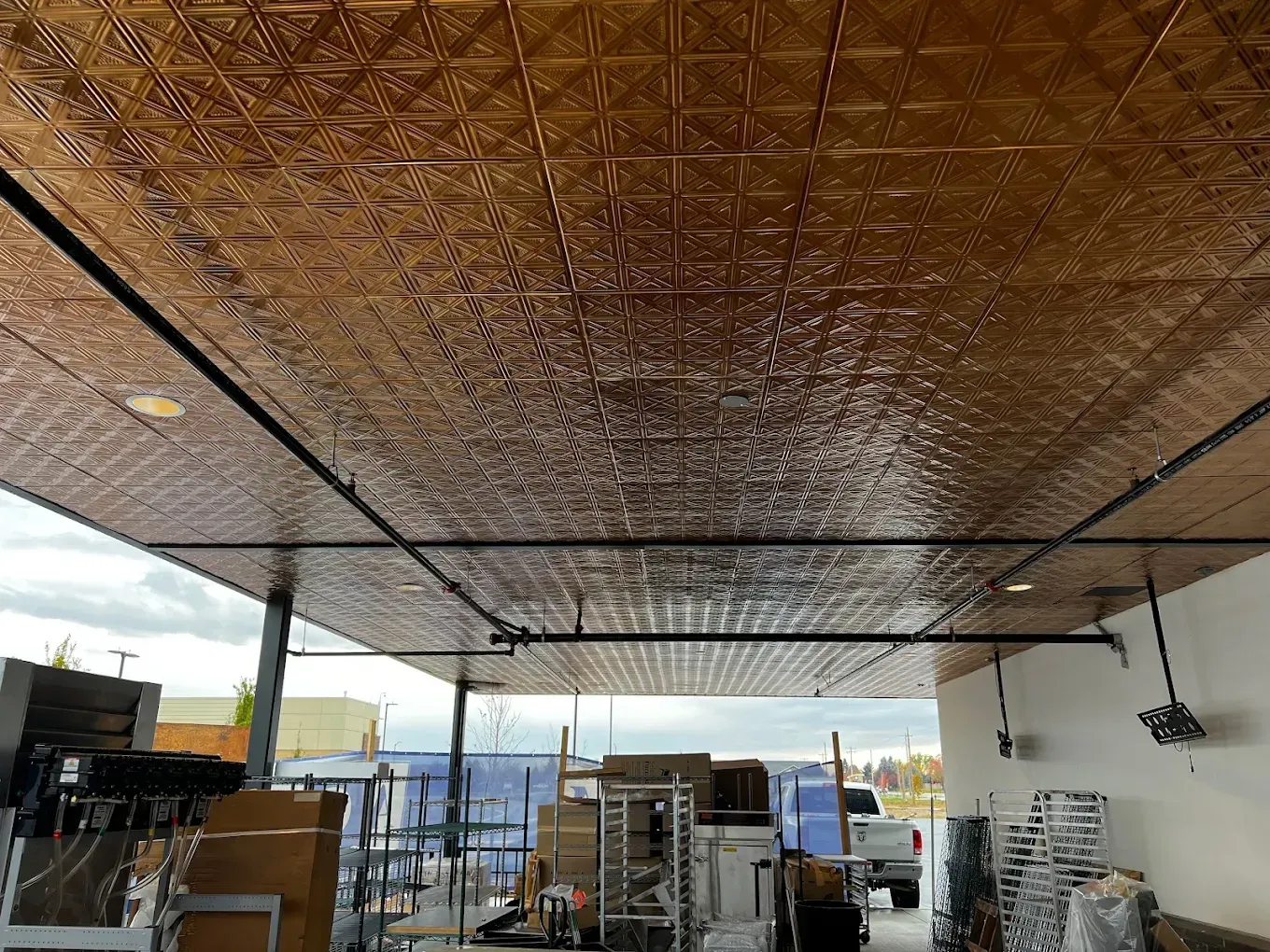 Construction site under a large woven canopy with scaffolding, tools, and materials in an open-air workspace