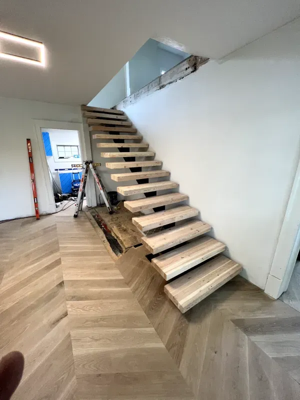 Indoor staircase under construction with unfinished wooden steps and a landing opening above.