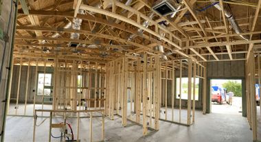 Interior of a house under construction with exposed wooden framing and unfinished walls