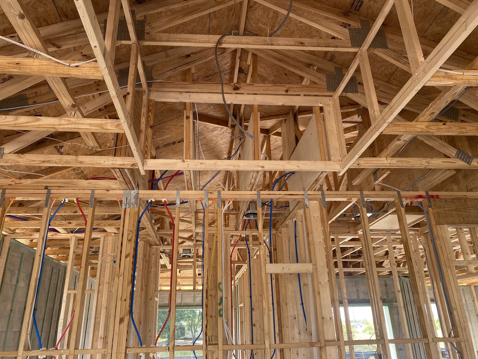 Interior of a wooden house under construction, showing exposed framing and roof trusses.