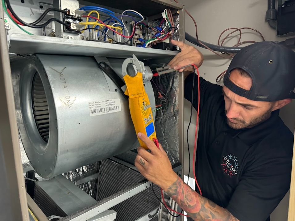 Technician using a yellow multimeter on a large metal HVAC unit with exposed wiring.