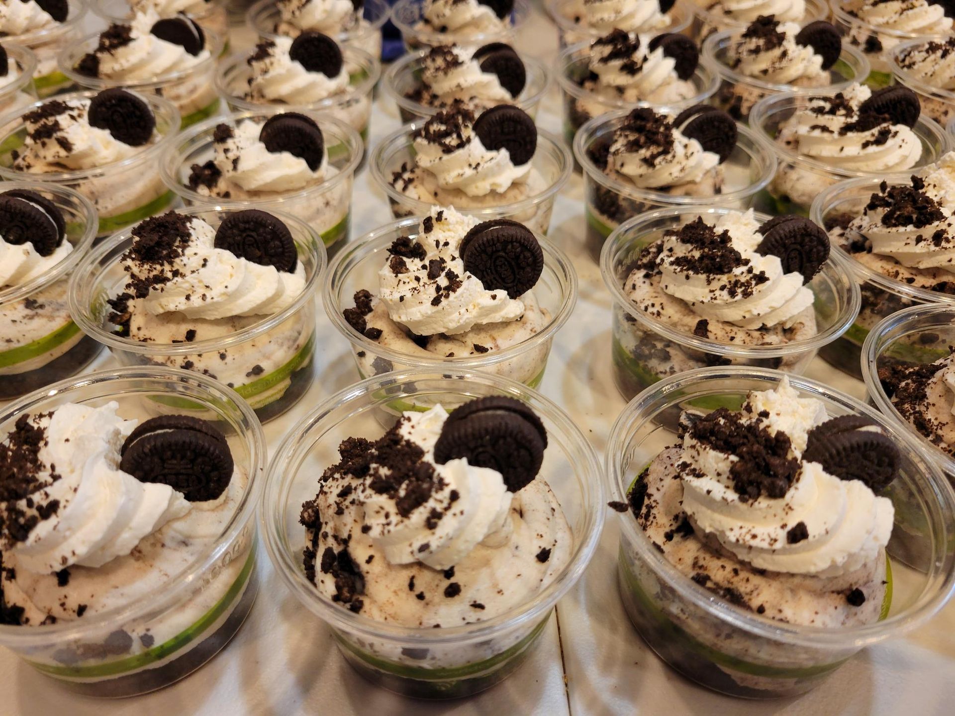 Rows of dessert cups topped with whipped cream and chocolate crumbs