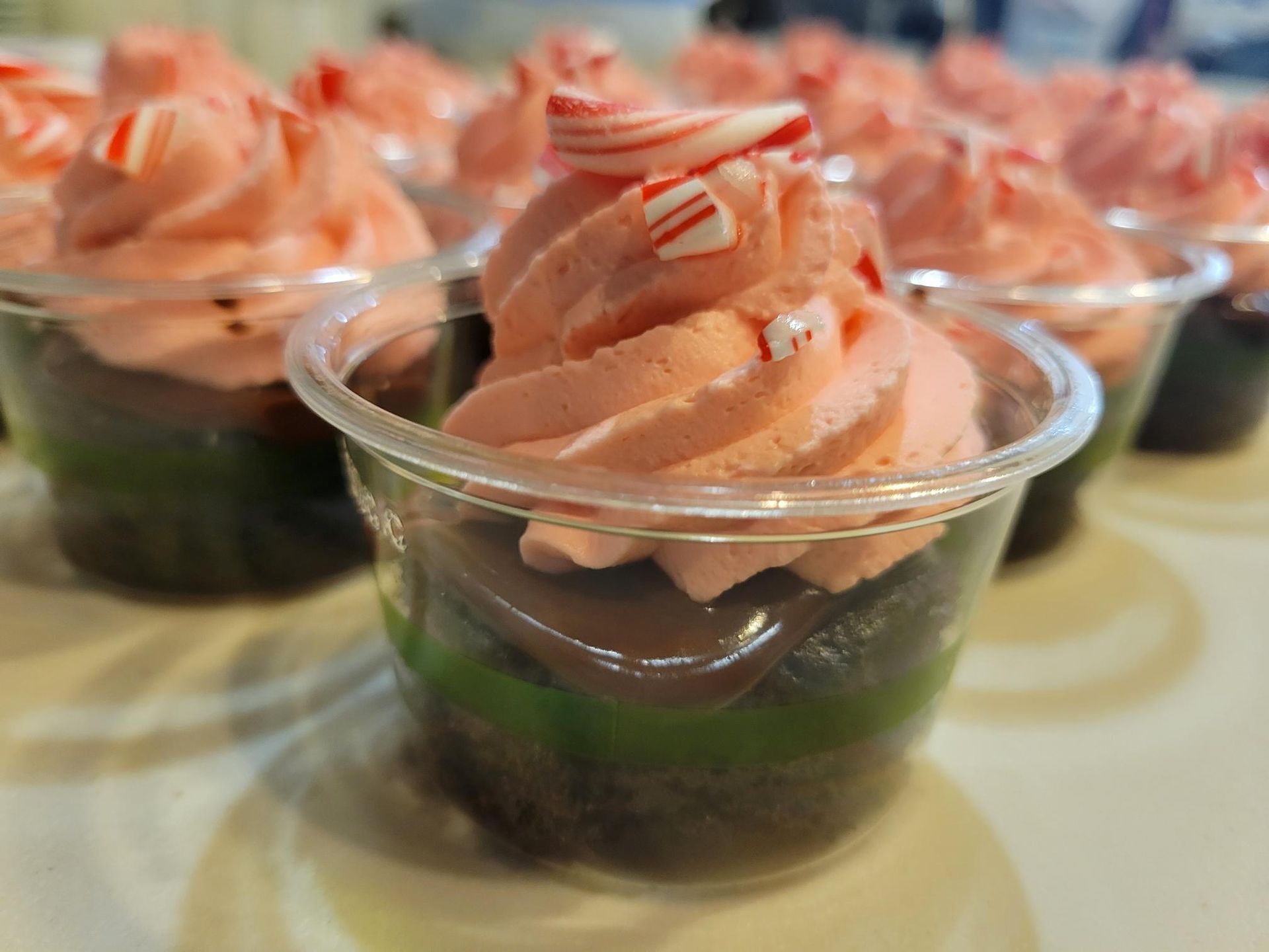 Dessert cups topped with swirled peach frosting and red drizzle