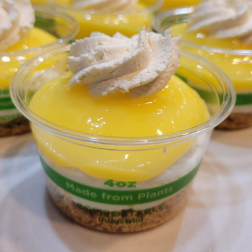 Mini lemon dessert jars topped with whipped cream and lemon slices on a counter