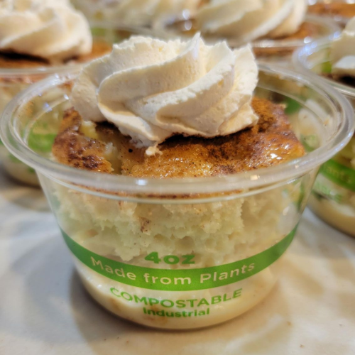Round dessert cup labeled “Tres Leches” with a clear lid and pastel label, stacked with others behind it