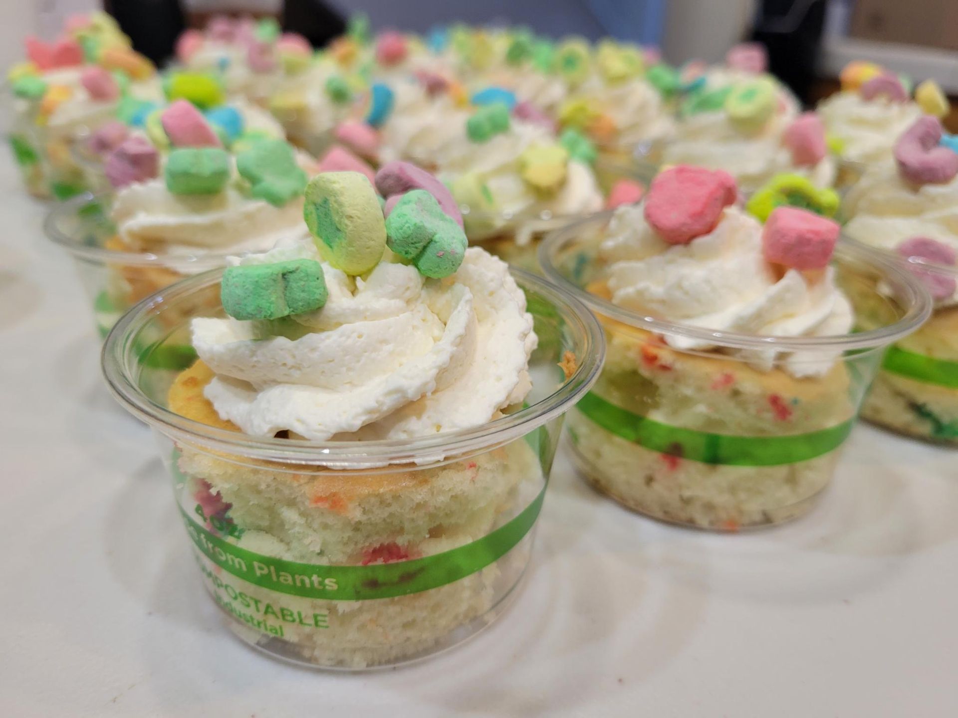 Clear cups of layered dessert topped with whipped cream and colorful marshmallows on a table