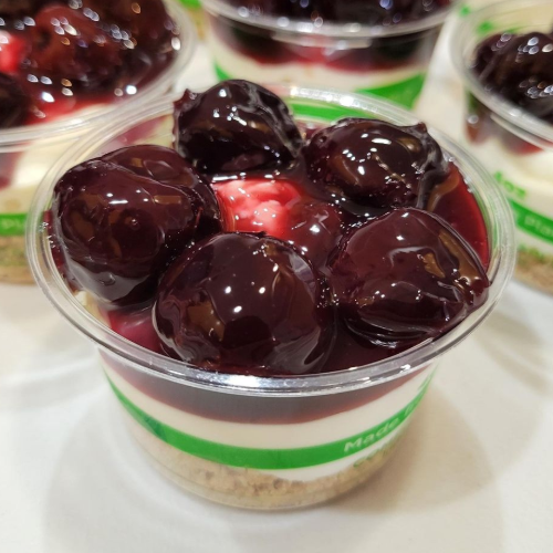 Layered dessert cups with red jelly topping and whipped cream on top